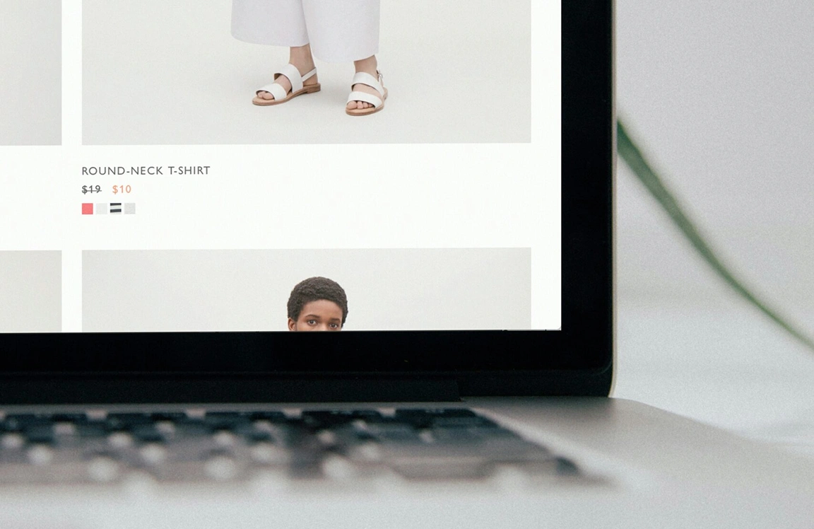 Laptop visar ett flöde av produktbilder i en klädwebbutik, med bilder på modeller.